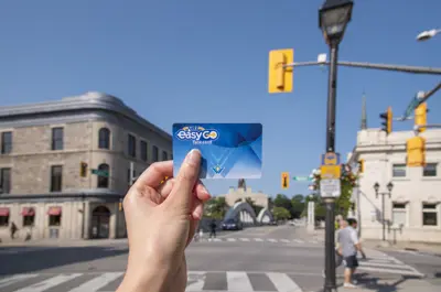 hand holding EasyGo fard card in front of an intersection with buildings