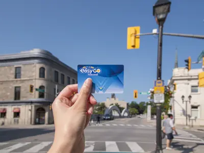 hand holding EasyGo fard card in front of an intersection with buildings