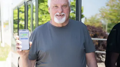 man standing next to a bus holding a cell phone
