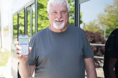 man standing next to a bus holding a cell phone
