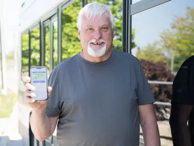 man standing next to a bus holding a cell phone