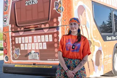 Indigenous person standing in front of the Every Child Matters bus