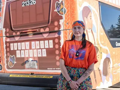 Indigenous person standing in front of the Every Child Matters bus